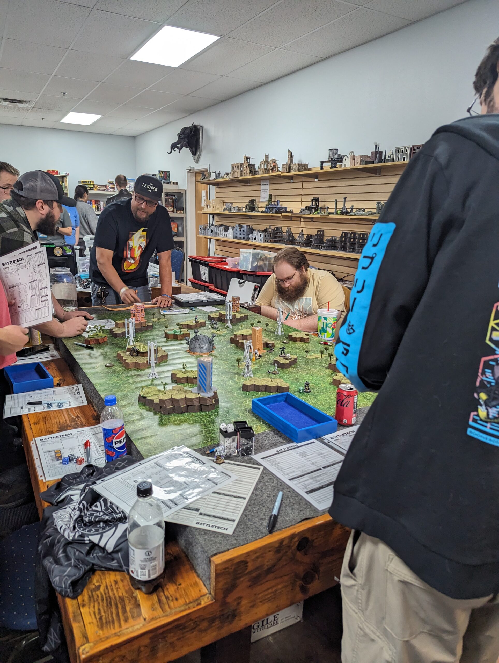 A group of people play Battletech around a table.